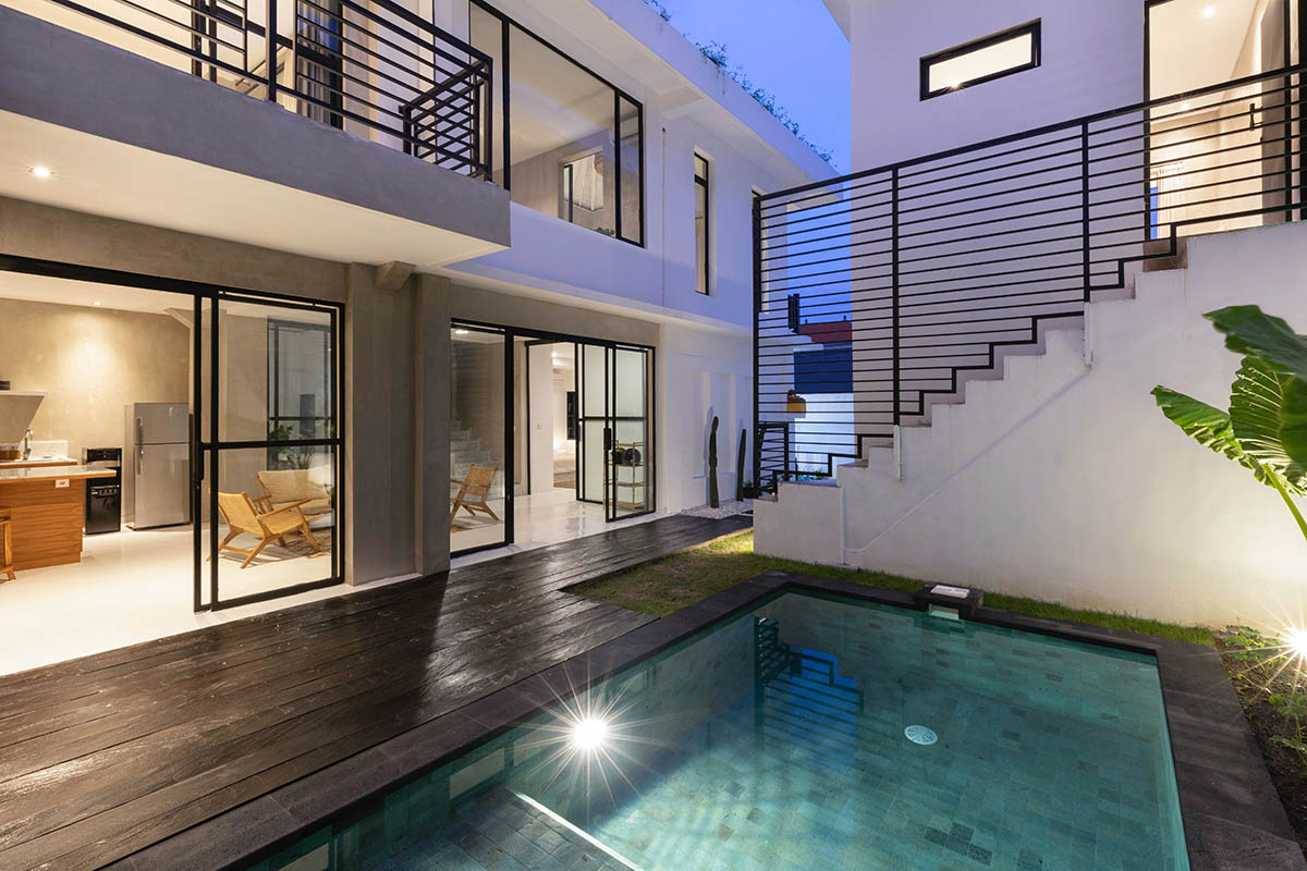White modern concrete building with bold black accents and a pool. Shown at night