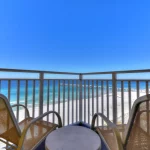 Two chairs and small table on a balcony overlooking the beach