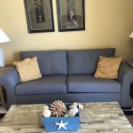 Blue couch with end tables, lamps, and a coffee table with nautical decorations