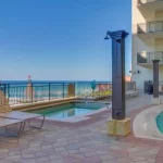 Hotel pool and hot tub with rinse off stations overlook the beach