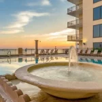 Bowl fountain within hotel pool overlooking the ocean at sunset