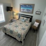 High view of smaller bedroom containing a tv, nightstand, bed, and chair