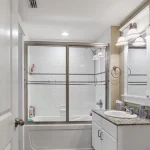 Bathtub and shower combo with sink counter in tan bathroom