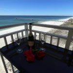 Wine set up for two on a table on a balcony overlooking the beach