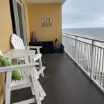 Balcony overlooking the beach with wooden tall beach chairs and table