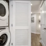 Stacked Whirlpool dryer and washer combo tucked into a double door closet space