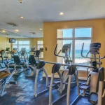 Gym room with yellow walls, a wall of mirrors, and various workout equipment