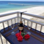 Wine set up for two on a table on a balcony overlooking the beach