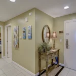 Entryway to an apartment with a view of a bedroom through an open bedroom