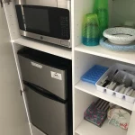 Shelving with mini fridge, microwave, and various kitchen utensils