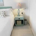 Bed with white bedding blue night stand with a lamp