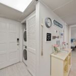 Entryway with a stacked washer and dryer in the closet and a hallway leading into a bedroom